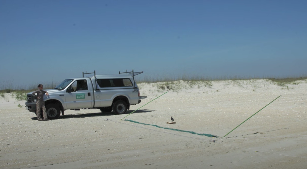Field truck parked on a beach and a whoosh net set up.